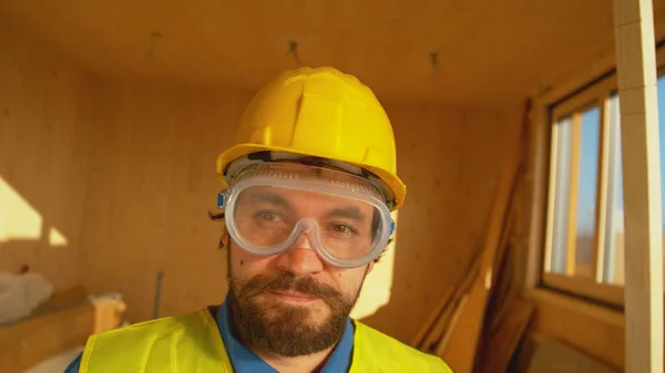Νέος εργολάβος που φοράει προστατευτικά σταντ σε ξύλινο σπίτι. — Φωτογραφία Αρχείου