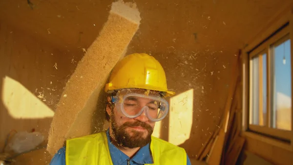 Sert bir şapka takan inşaat işçisi bir parça köpükle vuruluyor. — Stok fotoğraf