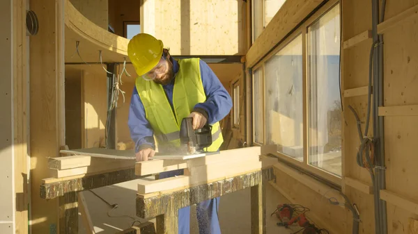 ΚΛΕΙΣΙΜΟ: Εργαζόμενος χτίζοντας ένα σπίτι από σκληρό ξύλο κόβει μια γυψοσανίδα. — Φωτογραφία Αρχείου