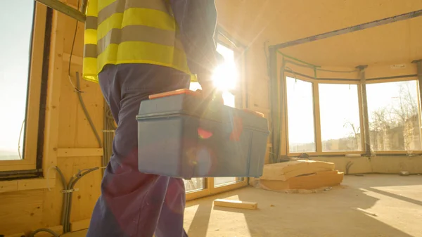 CLOSE UP: Golden sunbeams shine on worker coming to work in prefabricated house.
