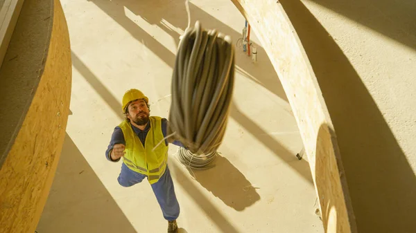 Giovane appaltatore cattura impianto elettrico tubi che cadono dall'alto. — Foto Stock