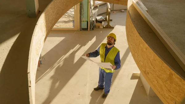 Architetto tenendo i suoi piani guarda il soffitto della casa CLT in costruzione. — Foto Stock