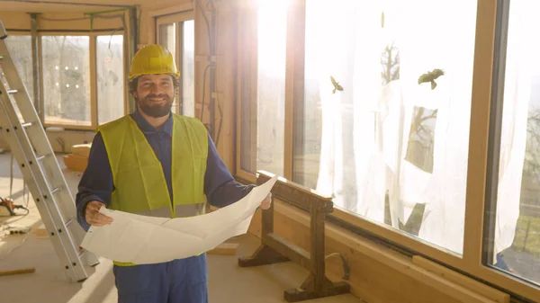 LENS FLARE: Διευθυντής εργοταξίου χαμογελά, ενώ κρατώντας τα σχέδια του ορόφου. — Φωτογραφία Αρχείου