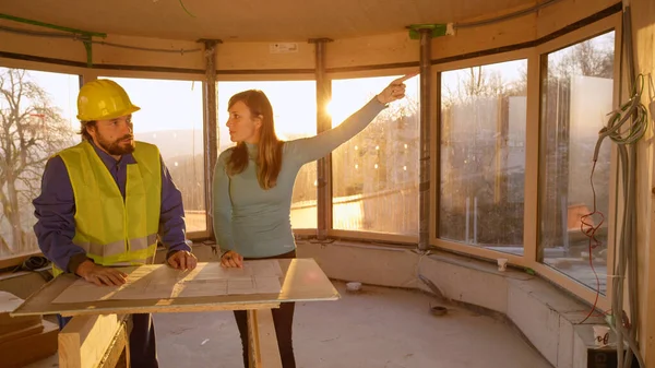 CLOSE UP: Ung kvindelig iværksætter skændes med arbejdstager over byggeplaner. - Stock-foto