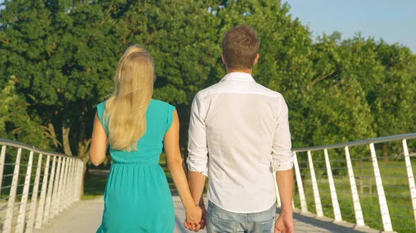 CLOSE UP Невпізнаваний чоловік і жінка в любові тримають руки під час перетину мосту — стокове фото