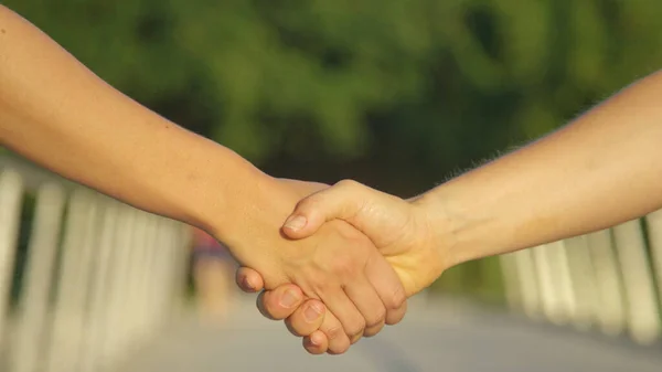 Oigenkännlig man och kvinna skakar hand på mötet i parken. — Stockfoto