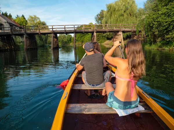 FECHAR-SE: Ativos turistas masculinos e femininos remar uma canoa sob uma ponte de madeira. — Fotografia de Stock