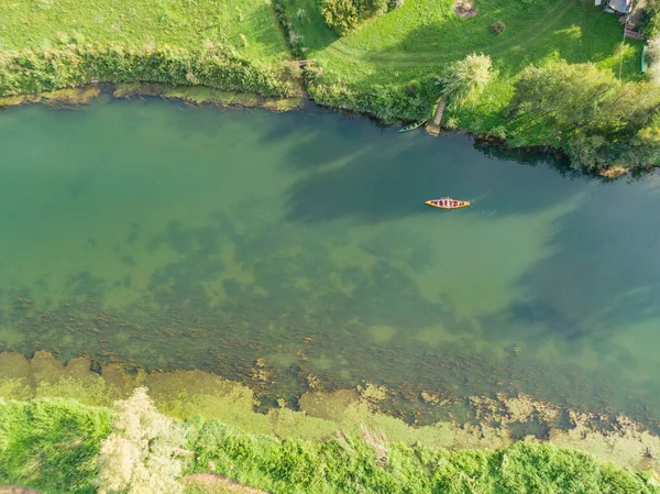 TOP DOWN: I turisti giacciono su una canoa mentre un amico li rema lungo un fiume pigro — Foto Stock