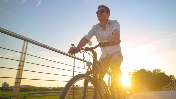 LENS FLARE: Beztroski człowiek cieszy się słoneczny letni wieczór jadąc na rowerze. — Zdjęcie stockowe