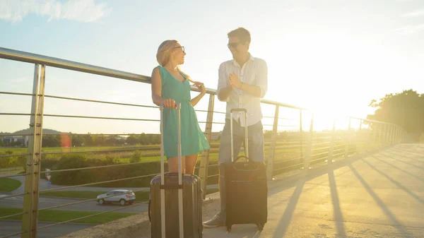 レンズフレア:若い新婚旅行は興奮して晴れた日に空港シャトルを待っています — ストック写真