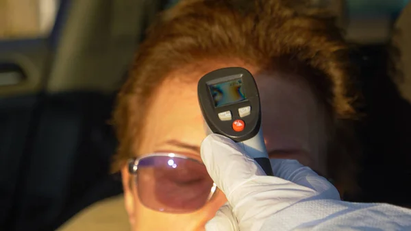 CLOSE UP, DOF: Elderly driver is pulled over to have her temperature measured. — Stock Photo, Image