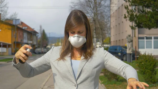 CERRAR: Mujer joven asustada con una máscara pulveriza desinfectante sobre sí misma. — Foto de Stock
