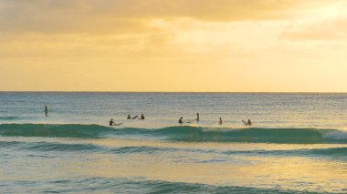 Barbados 'ta sörf yapan arkadaşlar gün batımında sırada beklerler.