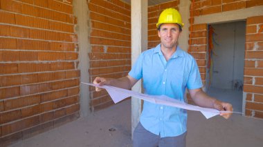 Müteahhit inşaat alanındaki ilerlemeden memnun olduğu için gülümsüyor..