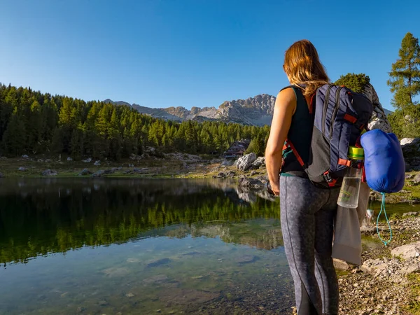 CHIUSURA: Donna irriconoscibile osserva il tranquillo lago alto delle Alpi Giulie. — Foto Stock