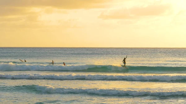 Surfeur masculin attrape une vague et la monte sur la côte par une soirée ensoleillée à la Barbade — Photo