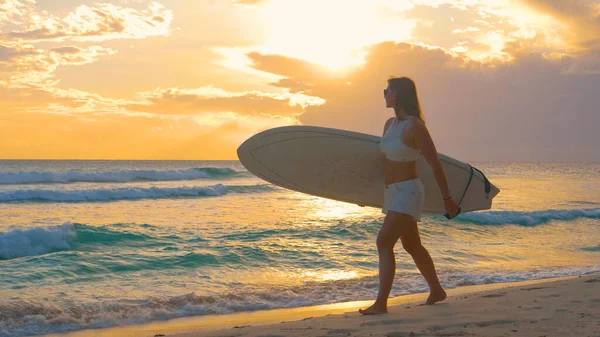 COPY SPACE: чудова туристична дівчина прогулюється піщаним пляжем з дошкою для серфінгу — стокове фото