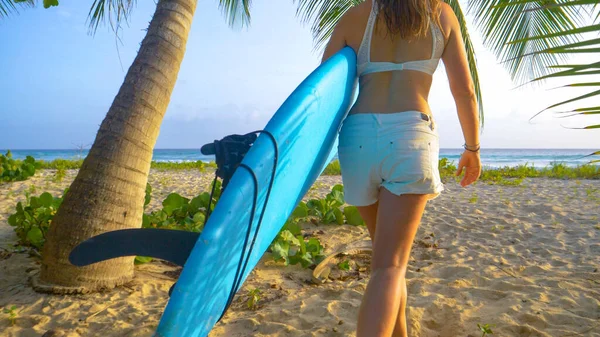 閉じる:女性サーファーは日没前にいくつかの波をキャッチするためにビーチに出て歩く. — ストック写真