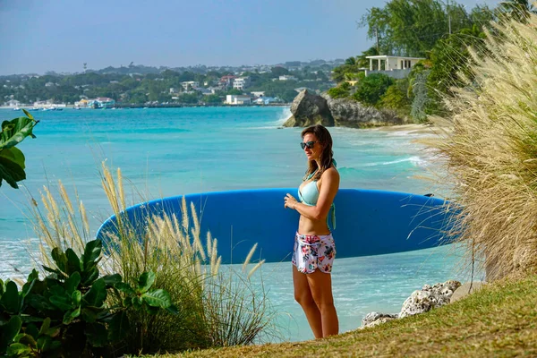 CERRAR: Mujer en vacaciones activas sostiene su tabla de surf mientras observa el océano —  Fotos de Stock