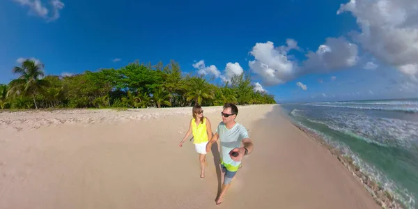Los recién casados despreocupados se toman de la mano mientras caminan por la playa de arena perfecta. —  Fotos de Stock