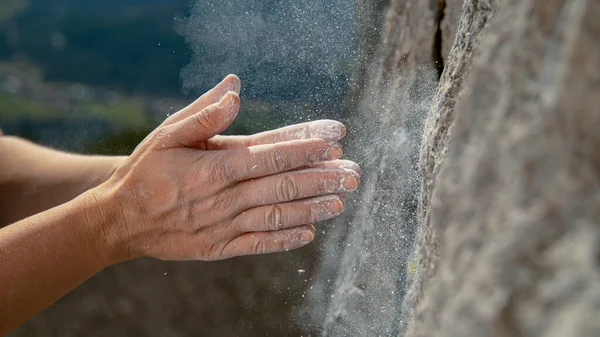 CLOSE UP: Unerkennbare Bergsteigerin klatscht in die Hände, um überschüssiges Magnesium loszuwerden. — Stockfoto