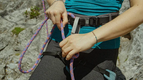 CLOSE UP: Vrouwelijke rots klimmer bindt belay touw aan het harnas voor haar klim — Stockfoto