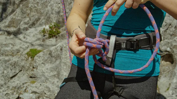 Close up: Γυναίκα δένει ένα σχοινί ασφαλείας γύρω από το λουρί πριν από την κορυφή αναρρίχηση σχοινί — Φωτογραφία Αρχείου