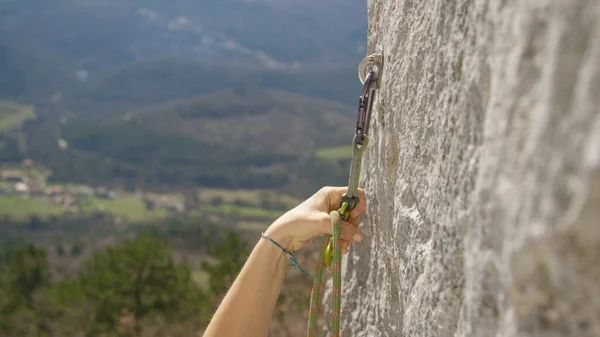 FECHAR-SE: Mulher loops sua corda do belay através de um mosquetão ao escalar acima do penhasco — Fotografia de Stock