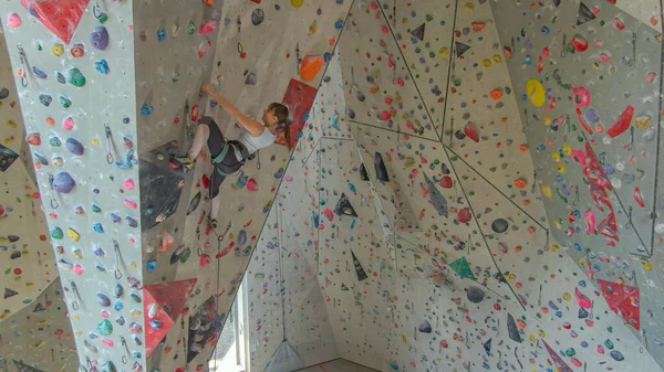 DRONE: Joven escaladora femenina escalando en un fresco centro de entrenamiento interior. — Foto de Stock