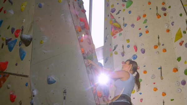 LENS FLARE: Bright sunbeams shine on a girl climbing a route in an indoor center