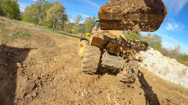 POV: El brazo de la excavadora recoge un cubo lleno de tierra y lo descarga en el remolque. —  Fotos de Stock