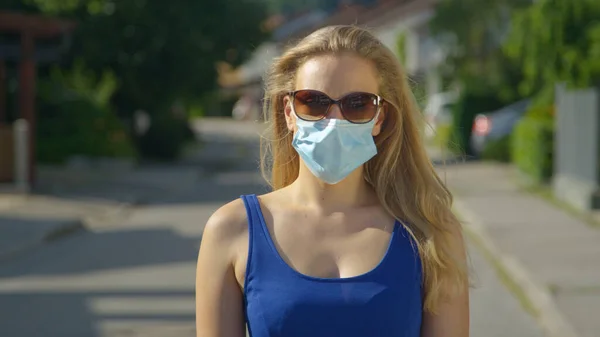 PORTRAIT: Mujer caucásica joven lleva gafas de sol y una máscara quirúrgica azul claro. —  Fotos de Stock