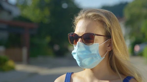 CERRAR: Mujer caucásica joven lleva gafas de sol y una máscara quirúrgica azul claro. —  Fotos de Stock