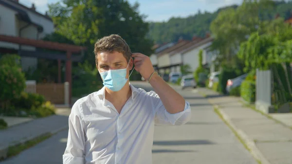 El tipo de pie en medio de la calle se quita la mascarilla.. — Foto de Stock