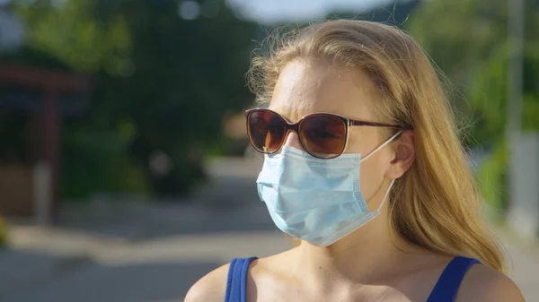 CERRAR: Mujer joven caucásica lleva gafas de sol y una mascarilla azul claro. —  Fotos de Stock