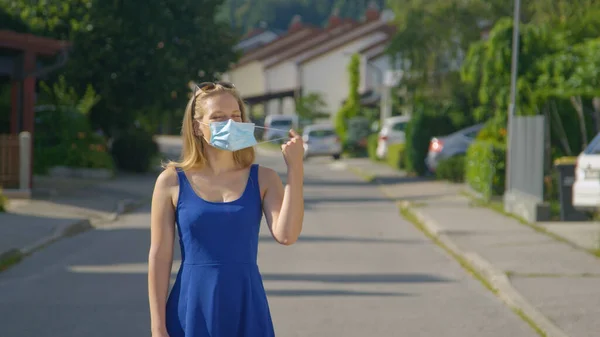 PORTRAIT: Niña de pie en medio de la calle se quita la mascarilla. —  Fotos de Stock