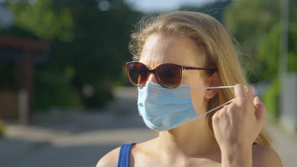 CERRAR: Joven mujer caucásica con gafas de sol se quita la mascarilla. —  Fotos de Stock