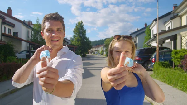 PORTRAIT: Smiling man and woman take off their masks and flick them at camera. — Stock Photo, Image