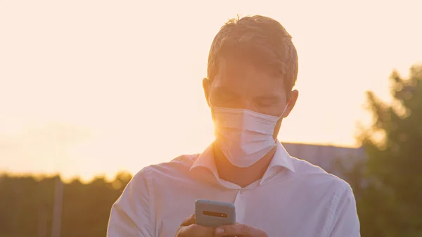 CERRAR: Joven con un texto de mascarilla médica en una soleada noche de verano. —  Fotos de Stock