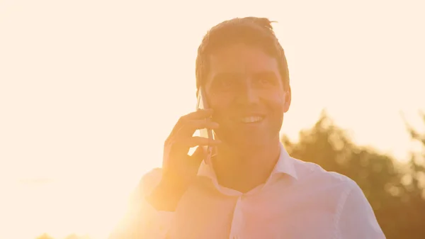 CLOSE UP: Successful businessman talks on the phone at golden summer sunset. — Stock Photo, Image