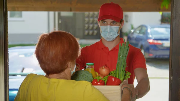 Yüz maskesi takan adam yaşlı bayana taze organik ürün getiriyor.. — Stok fotoğraf