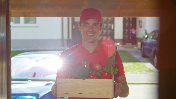 PORTRAIT: Cheerful man delivers a box of groceries at your doorstep on sunny day — Stock Photo, Image