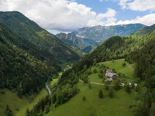 AERIAL: Vliegen over een kleine boerderij op de top van een heuvel in het schilderachtige Logarska Valley. — Stockfoto