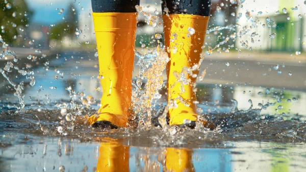 CLOSE UP: Beautiful glassy water splashes everywhere after woman jumps in puddle — Stock Photo, Image
