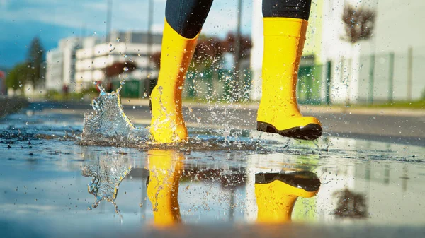 LOW ANGLE: Unrecognizable joyful girl runs across a puddle on the empty road. — Stock Photo, Image