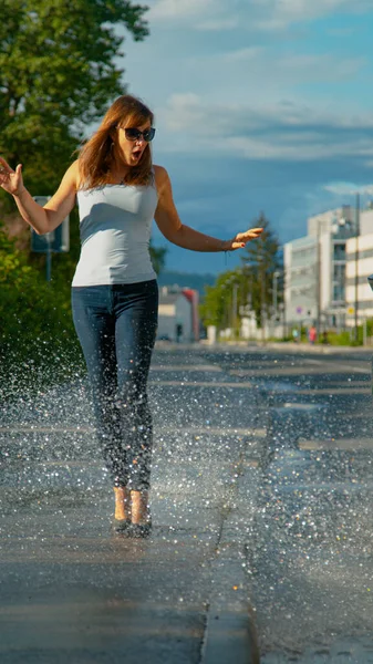 VERTICAL: Woman is shocked as she gets splashed with water by careless driver — Stock Photo, Image