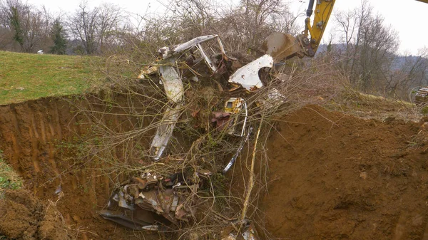 閉じる:ラスティ車の部品と野生の低木は茶色の土壌に埋葬されます. — ストック写真