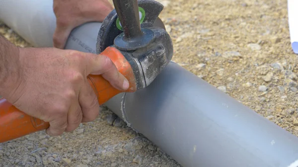 CLOSE UP: Неузнаваемый сантехник использует угловую решетку, чтобы перерезать PVC канализационную трубу. — стоковое фото