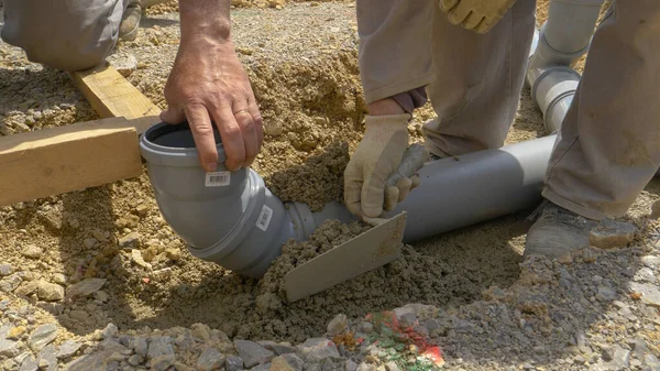 FECHAR UP: Um grupo de construtores enterrar um tubo de esgoto de plástico largo com concreto. — Fotografia de Stock