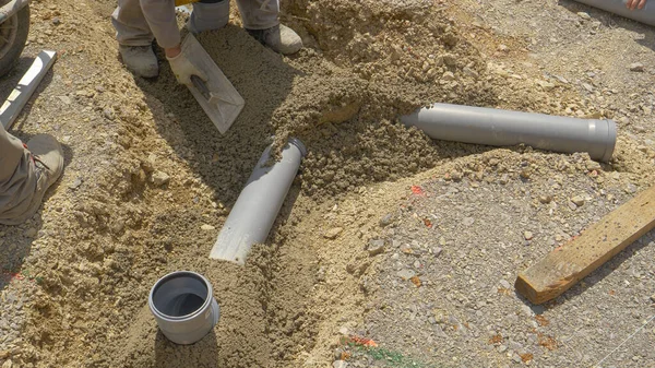ZAMKNIJ: Grupa nierozpoznawalnych wykonawców montuje nowy rurociąg kanalizacyjny. — Zdjęcie stockowe